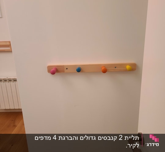 מתלה עץ עם ווים צבעוניים על דלת לבנה